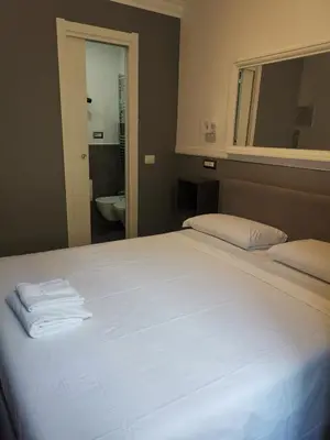 a large white bed in a bedroom with a mirror at I LOVE ROMA Guest House in Rome