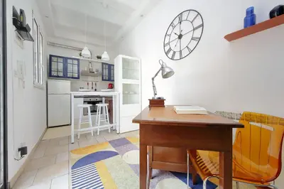 a room with a desk and a kitchen with a clock on the wall at Rifugio segreto nel cuore di Roma in Rome