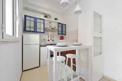 a white kitchen with a white counter and stools at Rifugio segreto nel cuore di Roma in Rome