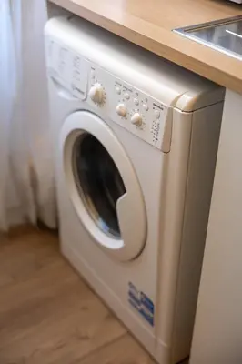a white washing machine sitting under a counter at The Heartbeat of Bohemian Rome in Rome