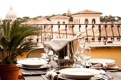 a table with plates and wine glasses on a balcony at St Peter Vatican wonderfull view apartment in Rome