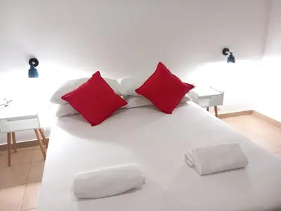 a white bed with two red pillows on it at TravelR's Home in Rome