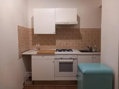 a kitchen with white cabinets and a stove and a blue stool at TravelR's Home in Rome