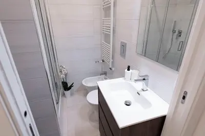 a white bathroom with a sink and a toilet at Domus Aurea2 a stone's throw from the Colosseum in Rome
