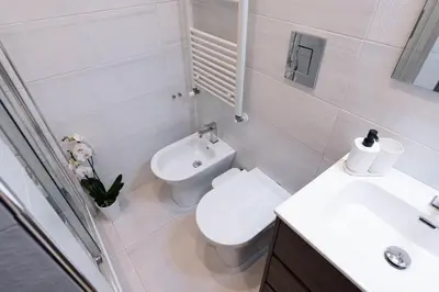 a white bathroom with a toilet and a sink at Domus Aurea2 a stone's throw from the Colosseum in Rome
