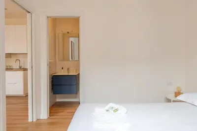 a bedroom with a white bed and a kitchen at Dante Art Home in Rome