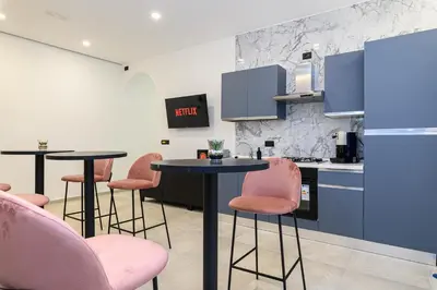 a kitchen with pink chairs and a table and counters at Vittorio Emanuele Art Suites in Rome