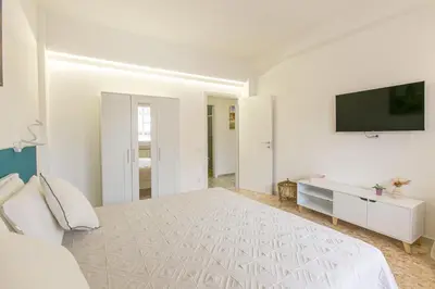 a white bedroom with a bed and a flat screen tv at Casa Leone in Rome