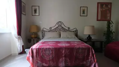 a bedroom with a bed with a red blanket and two lamps at B&B Caput Mundi in Rome