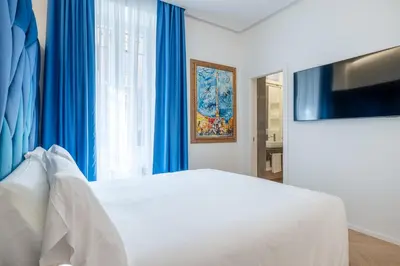 a bedroom with a white bed and blue curtains at Scipioni 235 Luxury Suite in Rome