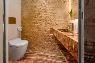a bathroom with a toilet and a stone wall at Locanda da Enzo in Rome