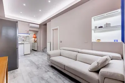 a living room with a white couch and a kitchen at LuxurySistersHouse 2 min Colosseum in Rome