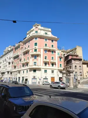 a pink building with cars parked in front of it at Around The Corner Colosseo B&B in Rome