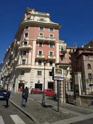 a large pink building with people walking in front of it at Around The Corner Colosseo B&B in Rome