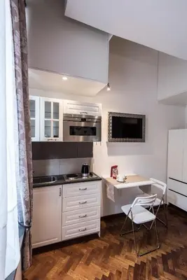a kitchen with white cabinets and a table and chairs at Vite Suites Guest House in Rome