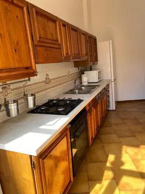 a kitchen with wooden cabinets and a stove top oven at La Casa di Ester Three-room apartment in Rome