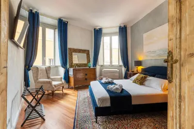 a bedroom with a bed with blue curtains and a chair at RomanticRome, elegant apartment in Trastevere district in Rome