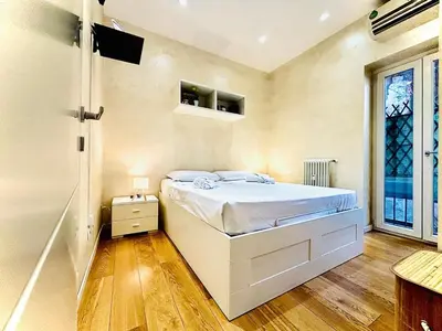 a white bedroom with a bed and a window at Monti Hideaway - Walk to Colosseum & Forum in Rome