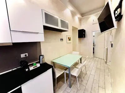 a small kitchen with a green table and white cabinets at Monti Hideaway - Walk to Colosseum & Forum in Rome