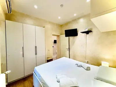 a bedroom with a large white bed and cabinets at Monti Hideaway - Walk to Colosseum & Forum in Rome