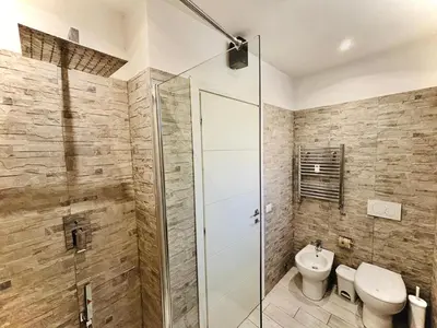 a bathroom with a toilet and a glass shower stall at Monti Hideaway - Walk to Colosseum & Forum in Rome