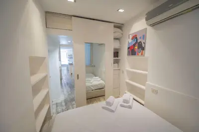 a white bedroom with a bed and a mirror at Elegant Design Retreat by Campo de Fiori in Rome