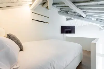 a white bedroom with a bed and a tv at Skylife Monti's Wonders - Colosseum Gem in Rome