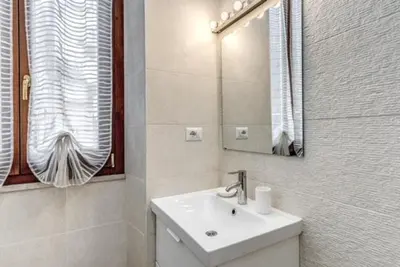 a white bathroom with a sink and a mirror at Loft in the Ghetto 2 in Rome