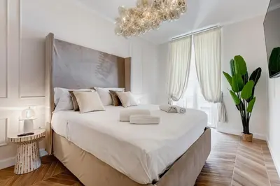 a white bedroom with a large bed with a chandelier at Vatican Design Apartment - NEW! in Rome