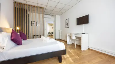 a bedroom with a bed and a desk and a television at Flat 5 - In San Giovanni by Rentbeat in Rome