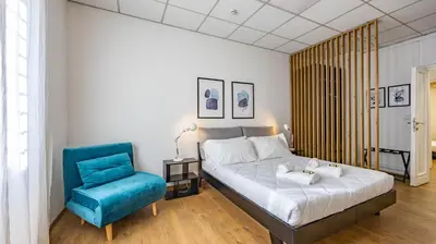 a bedroom with a bed and a blue chair at Flat 5 - In San Giovanni by Rentbeat in Rome