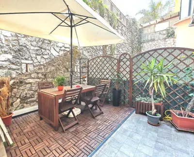 a patio with a wooden table and an umbrella at Piramide Charming Flat e Terrace in Rome