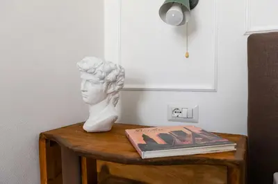 a statue of a bust on a table with a book at Domus Gabriella - Roman Forum Apartment in Rome