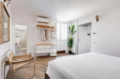 a white bedroom with a bed and a chair at Domus Gabriella - Roman Forum Apartment in Rome