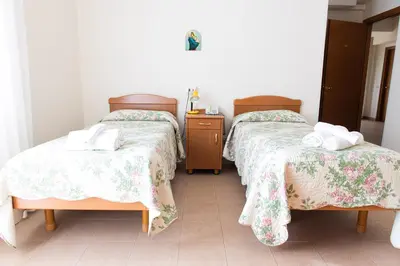 a room with two beds and a table with towels at Villa Santa Emerenziana in Rome