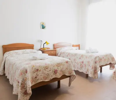 a bedroom with two beds and a table with two towels at Villa Santa Emerenziana in Rome