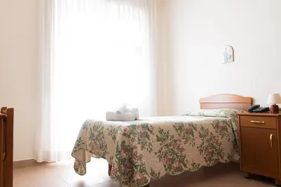 a bedroom with a bed and a dresser and a window at Villa Santa Emerenziana in Rome