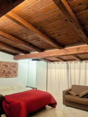 a bedroom with a red bed and a couch at Monolocale loft ristrutturato- Metro Manzoni in Rome