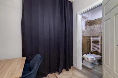 a bathroom with a toilet and a black shower curtain at Vogue Suites Rome in Rome