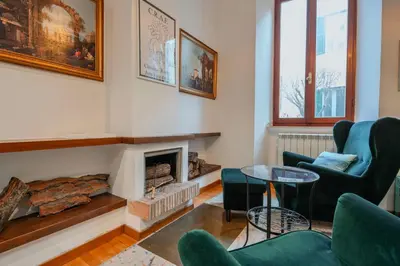 a living room with a fireplace and green chairs at Villa Classical Roman Art - Monteverde with Garden in Rome