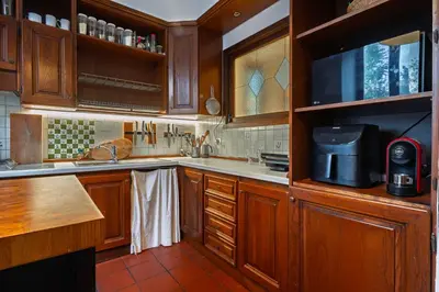 a kitchen with wooden cabinets and a microwave at Villa Classical Roman Art - Monteverde with Garden in Rome