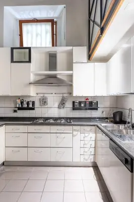 a white kitchen with white cabinets and a window at Roman Charme Spagna in Rome
