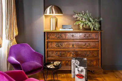 a room with a wooden dresser and a purple chair at Crossing Condotti in Rome