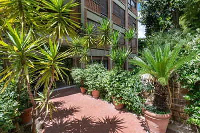 a garden with palm trees and plants in front of a building at ROMAN DREAM lll in Rome