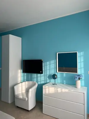 a living room with a white chair and a tv at F R Vatican view apartment in Rome