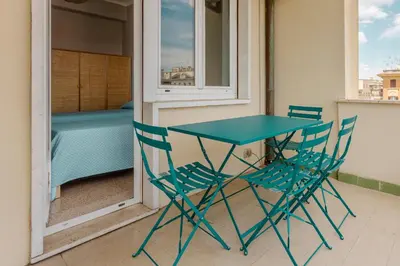 a table and chairs on a balcony with a bed at GuestHost - Re di Roma - Bright Apartment X4 in Rome
