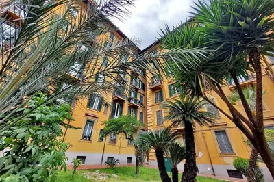 a yellow building with palm trees in front of it at Attico Luminoso Bed in Bormida in Rome