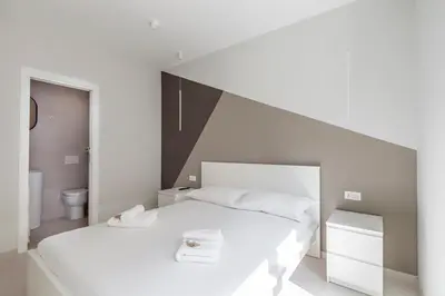 a white bedroom with a large bed and a toilet at Vatican Suites in Rome