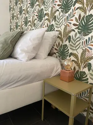 a bed with a side table with a clock on it at Appartamento Boho a San Lorenzo ,quartiere della street art in Rome