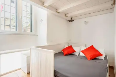 a white room with a bed with red pillows at La Casetta Aureliana in the center of the capital in Rome